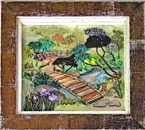 Embroidered trees and flowers in a park with a wooden bridge over a stream.